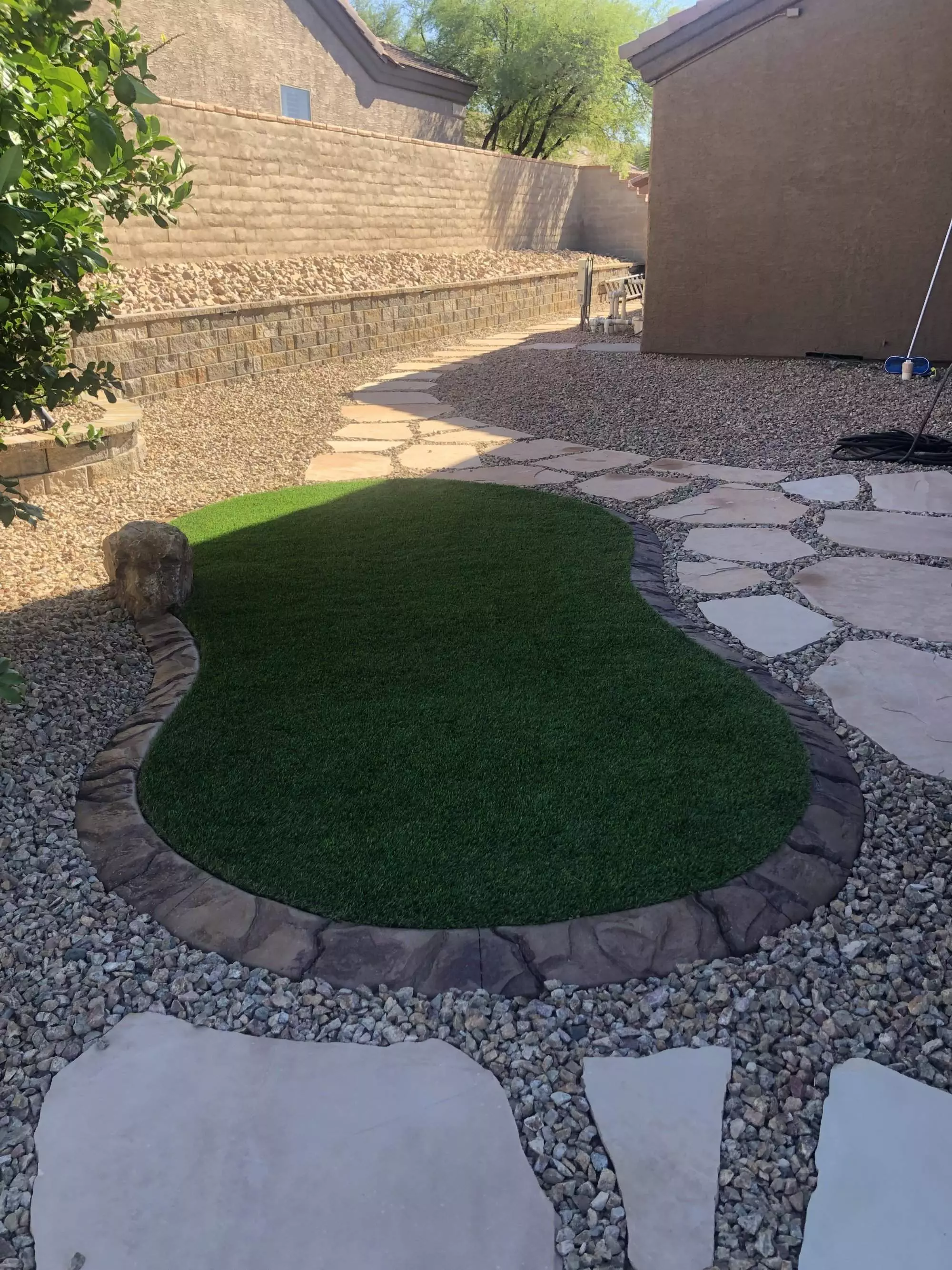 small area of artificial grass installation with custom concrete curbing and flagstone surrounding